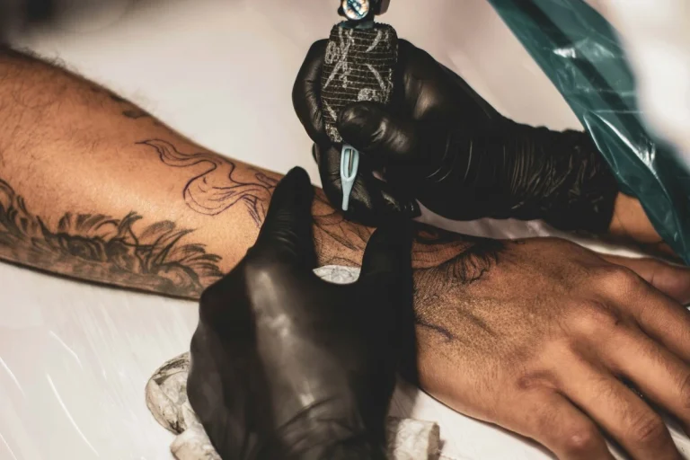 Tatuador cubriendo un tatuaje antiguo con un diseño nuevo haciendo un tatuaje cover up.